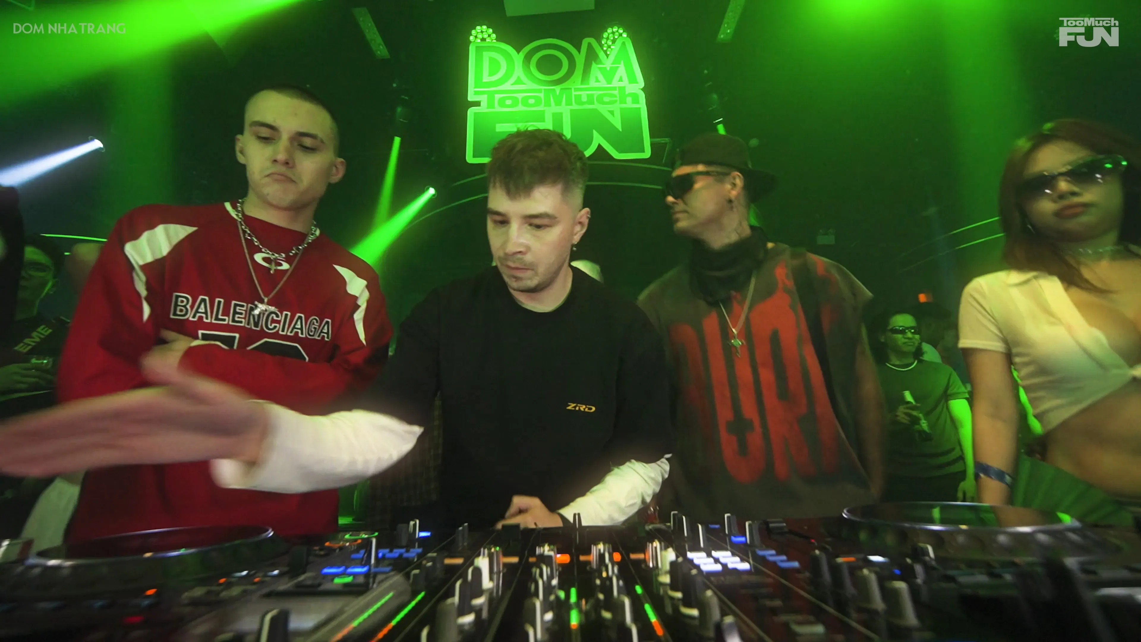 DJ performing under green light at DOM